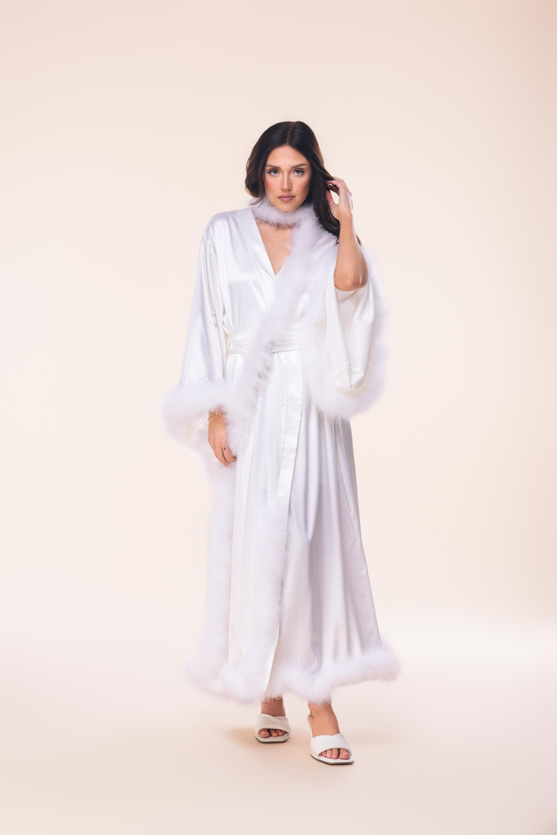 Woman wearing a white dress with sheer sleeves against a beige background