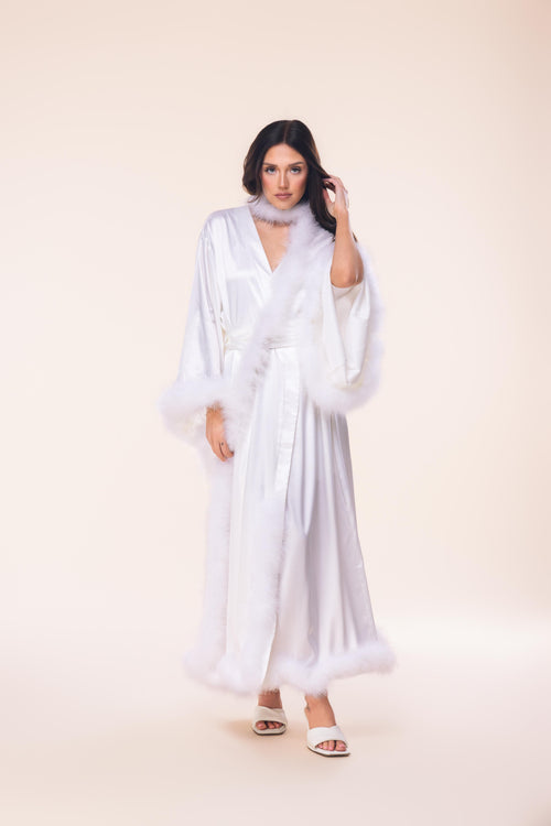 Woman wearing a white dress with sheer sleeves against a beige background