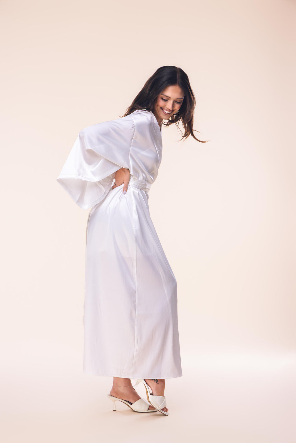 Woman wearing a white dress against a beige background