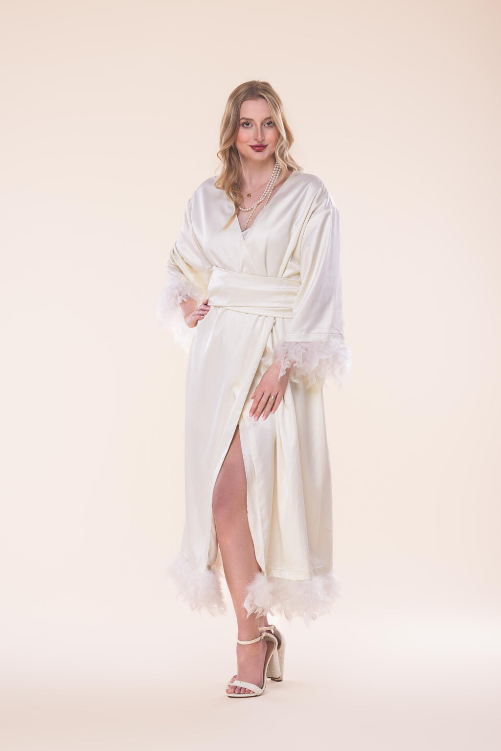 Woman wearing a white dress with sheer sleeves against a beige background