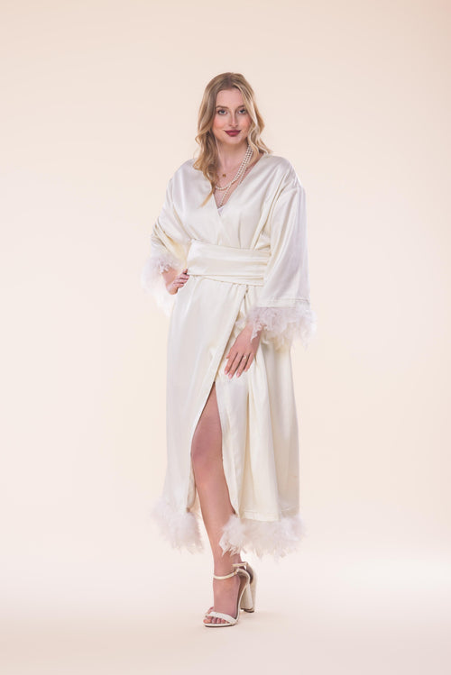 Woman wearing a white dress with sheer sleeves against a beige background