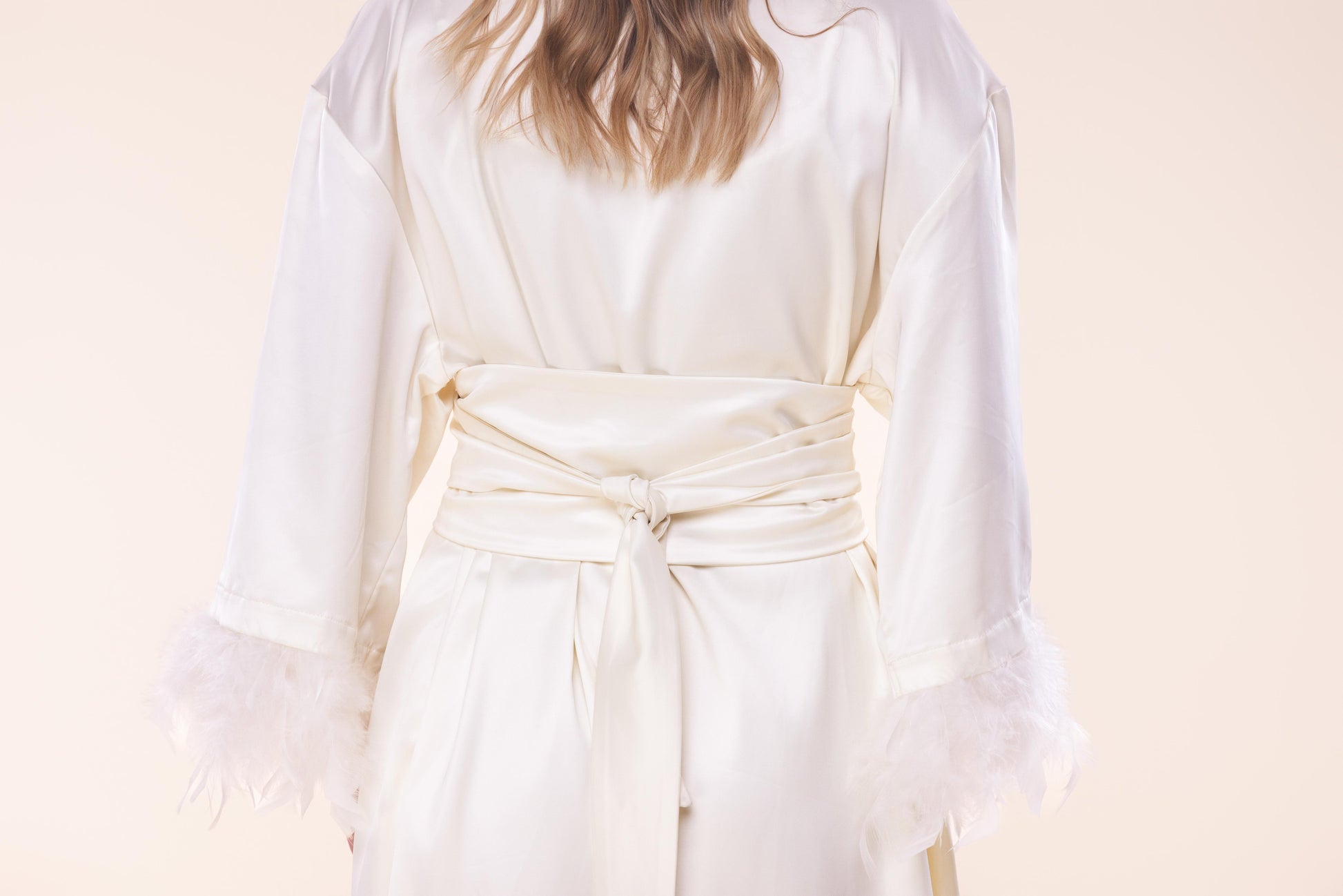 Person wearing a white robe against a plain background