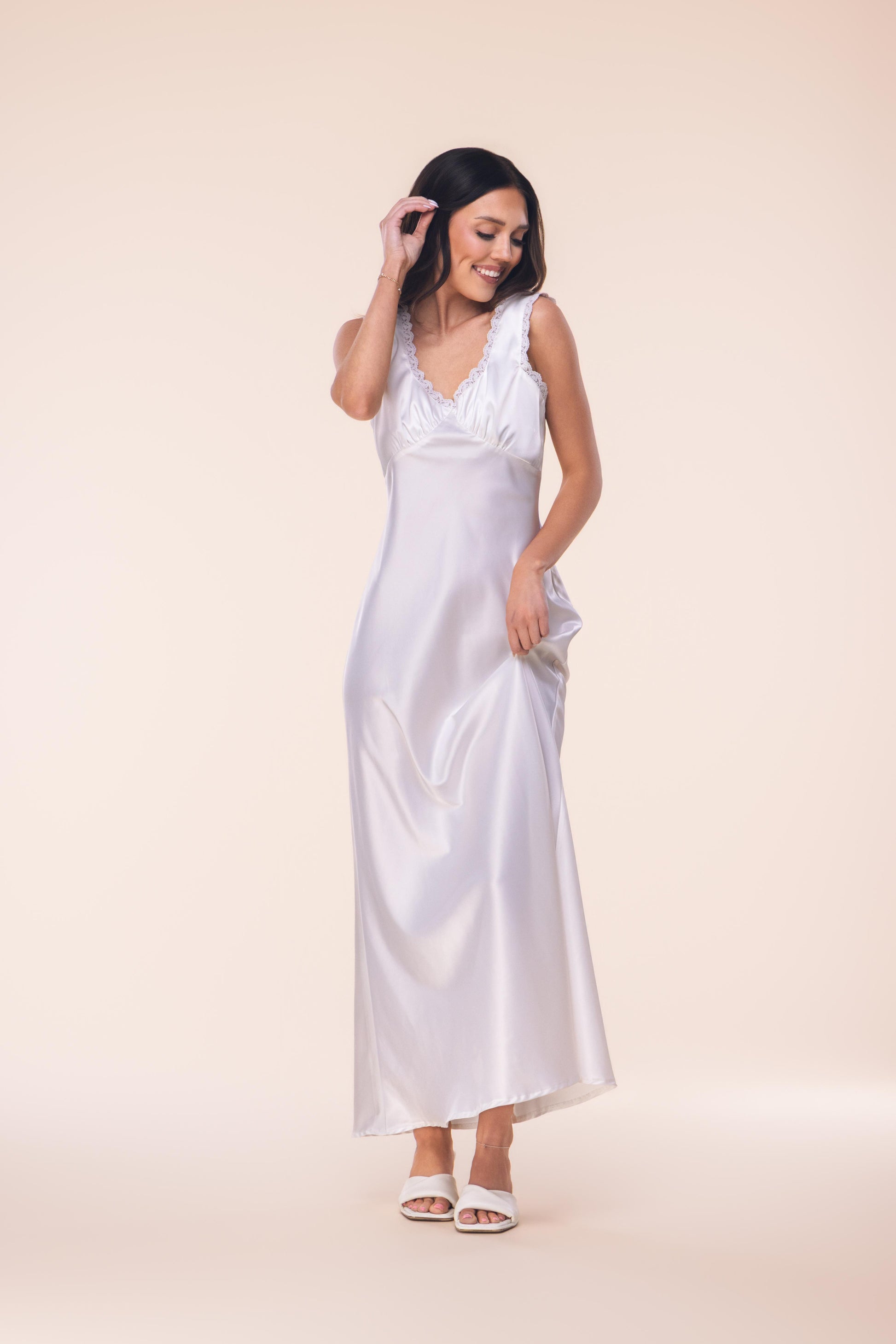 Woman wearing a white satin nightgown against a beige background