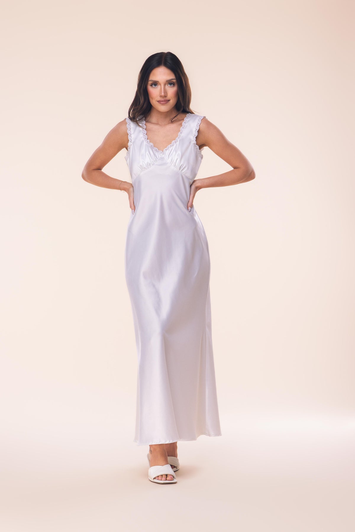 Woman wearing a white satin nightgown against a beige background