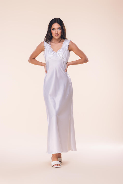 Woman wearing a white satin nightgown against a beige background