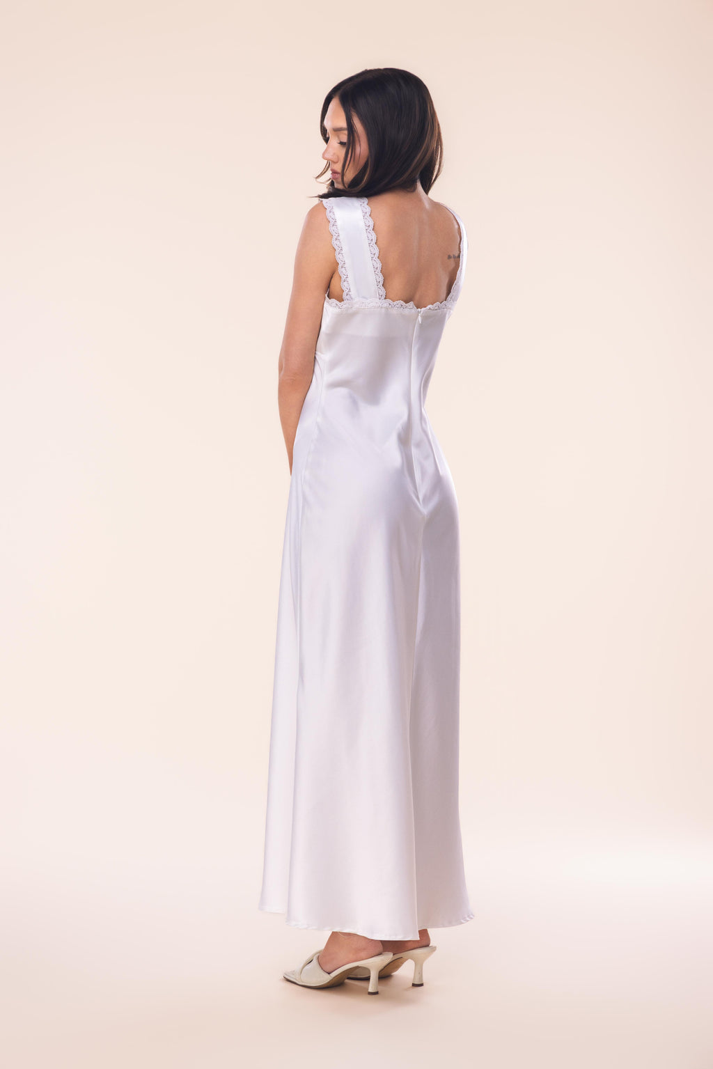 Woman wearing a white sleeveless dress on a beige background