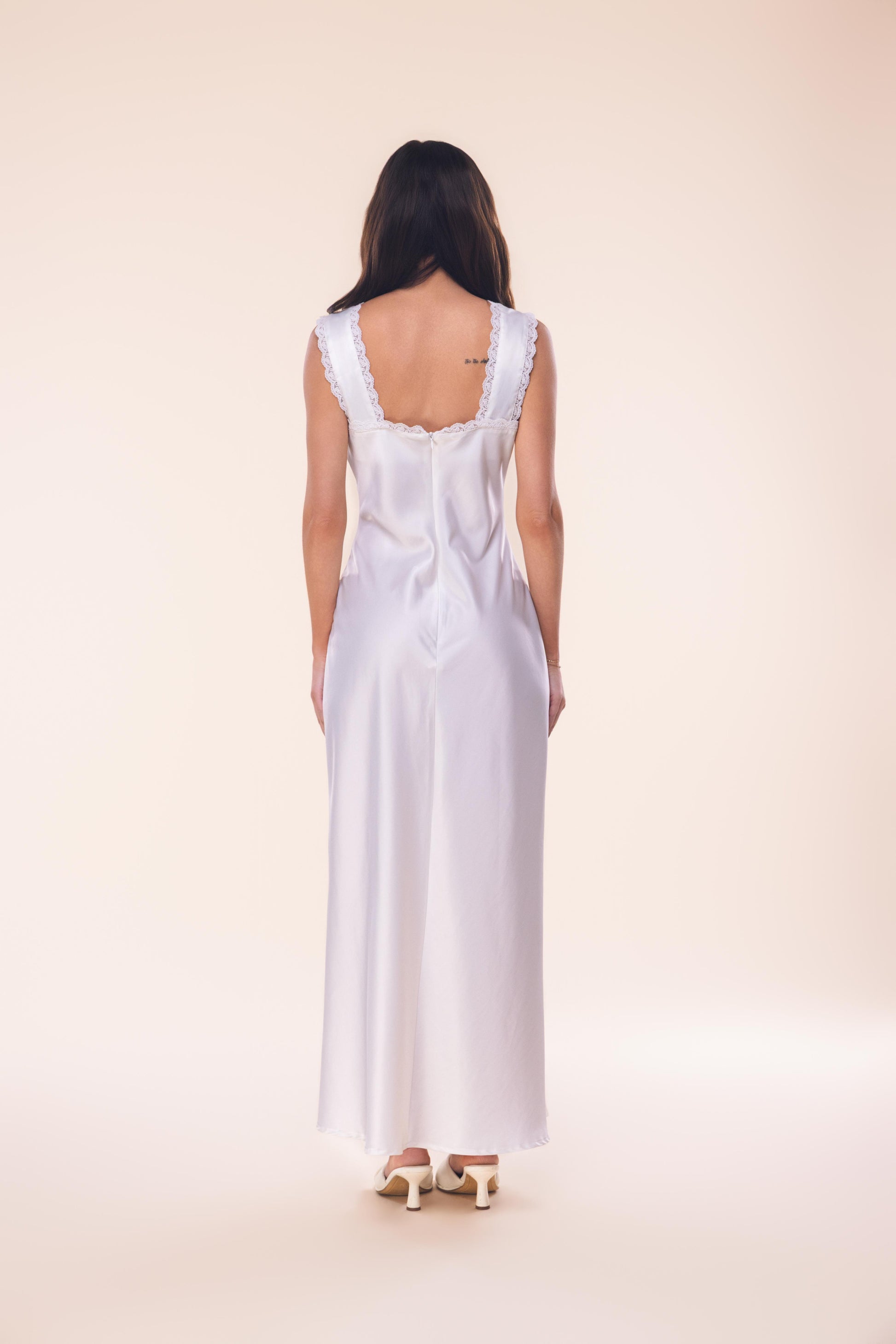 Woman wearing a white dress with a plain background